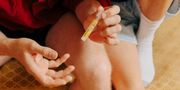 Paar sitzt auf Couch und entnimmt Blut fuer STI Heimtest scaled