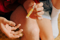 Paar sitzt auf Couch und entnimmt Blut fuer STI Heimtest scaled