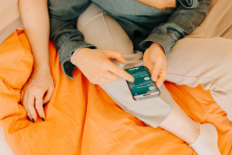 Paar im Bett checkt Ergebnis eines Tests auf sexuelle Infektionen am Handy