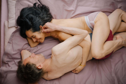 Paar schmust nackt im Bett